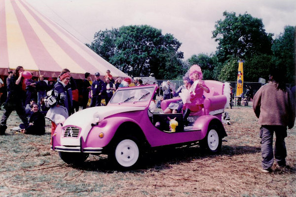 YA2a: Pink, open-top Citroën 2CV with pink armchair and pink drag queen on board