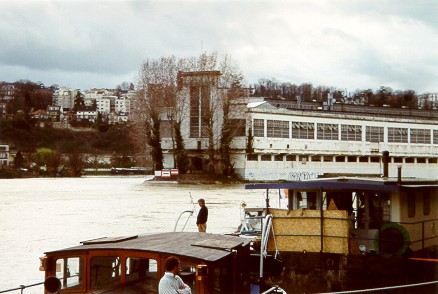 YA7a: Looking over the top of a barge to the factory on the river island